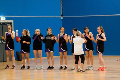 An umpire checking a line of netball players for jewellery and fingernails