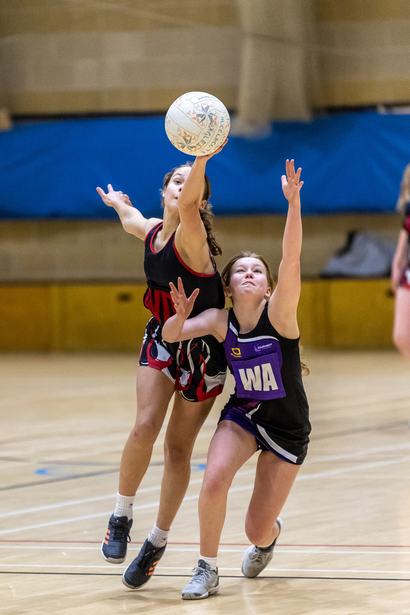 Junior netball players contesting for the ball in the air
